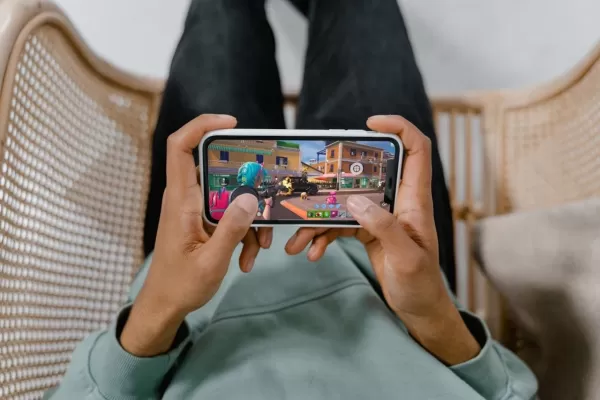 มือคู่หนึ่งถือโทรศัพท์เล่น Fortnite พร้อมทริกเกอร์แม่เหล็กติดกับโทรศัพท์